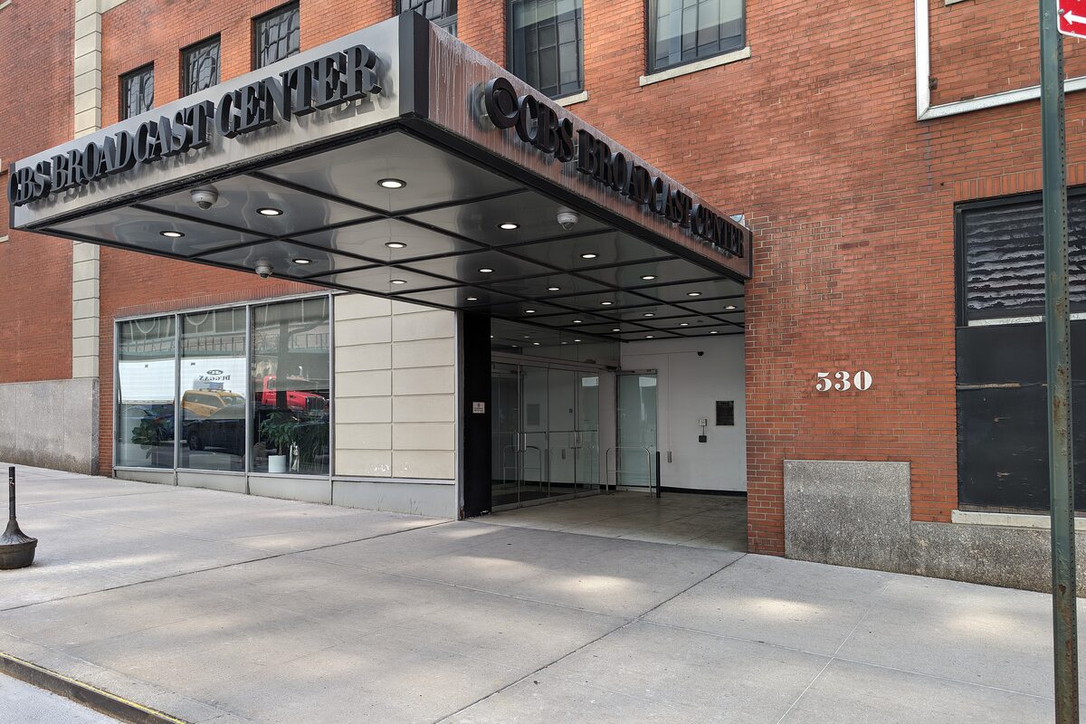 A brick building's entrance under a black metal canopy lettered CBS Broadcast Center, with the number 530 on the wall beside it.